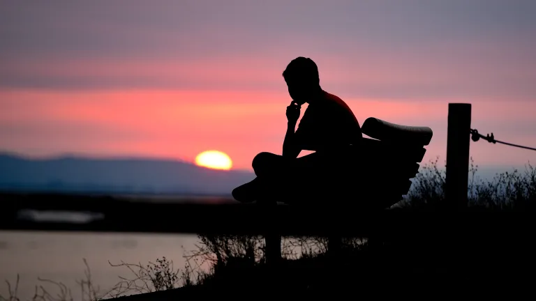 Faith is trusting belief, conviction and conduct based on a right relationship with God. A person sitting on a bench with the sun setting.